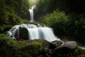 Cascade de Giessbach en pose longue, eau soyeuse sur deux paliers rocheux dans une foret verte (Suisse)